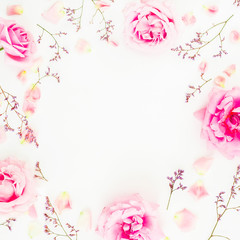 Round frame of pink roses and petals on white background. Flat lay, top view.