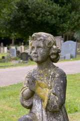 Praying child statue on grave in cemetery