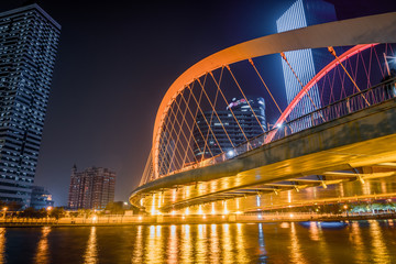 Tianjin Hai river waterfront downtown skyline with illuminated modern bridge,China