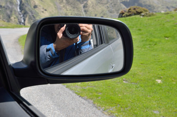 Wing mirror showing a camera in human hands