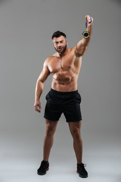 Full length portrait of a satisfied strong shirtless male bodybuilder