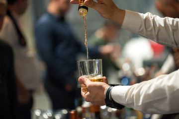 The barman pours alcohol into a glass.