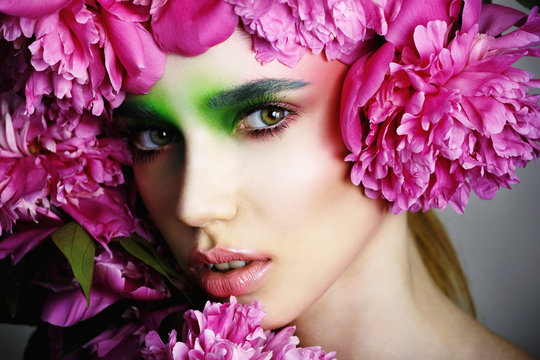 Young woman model with creative make-up around face flowers peonies. Fashion concept. Pink. Green.