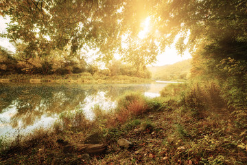 Beautiful sunny autumn landscape with reflection in the water and sun shine