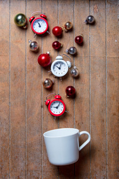 White cup on lying on side with baubles and alarm clocks