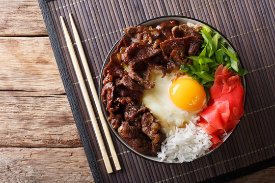 Gyudon beef with rice, egg and onion closeup in a bowl on the table. Horizontal top view