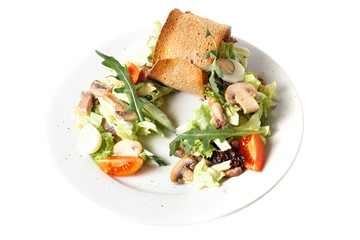 Close-up homemade fresh vegan vegetable salad with mushroom, quail egg, arugula, tomato, cucumber and bread toast. Round plate. Isolated on white
