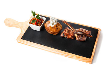 Fototapeta na wymiar Sliced grilled Deep rare barbecue Steak on bone rib with garnish - uncleaned grilled potato with parmesan cheese and vegetable salad with parsley. Isolated on white. Top view of wooden cutting plate