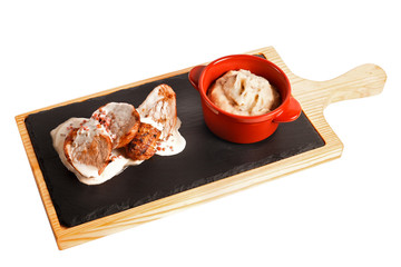 Mashed potatoes in bowl on wooden plate with grilled lamb in sauce with cream gravy. Ceramic base. Isolated on white