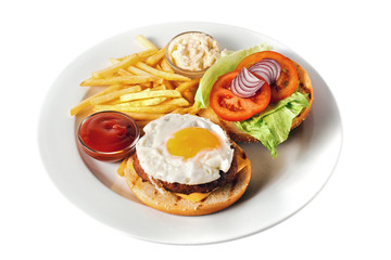 Delicious burger with grilled beef cutlet, cheese, scrambled eggs with yolk, tomato, onion, two kind of sauces and salad, as well as roasted potato. On a round plate. Isolated on white
