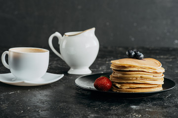 plate of delicious stacked pancakes with cup of coffee