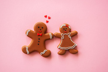 Festive Christmas concept background. Gingerbread man and girl on a pink backdrop. Top view.
