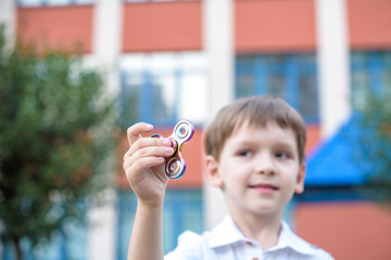 Cute little boy playing with fidget hand spinner in summer day. Popular and trendy toy for children and adult