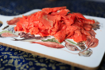 Closeup of thinly sliced smoked salmon on wooden board