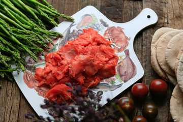 Closeup of thinly sliced smoked salmon on wooden board