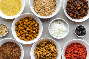 Vegetarian breakfast with healthy food selection, fruits, cereals, seeds, nuts, almonds, goji berries and other superfoods on table, flat lay, overhead
