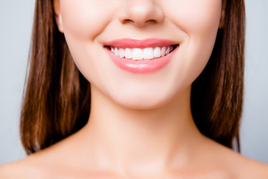 Concept of healthy wide beautiful smile. Cropped close up photo of healthy without caries shiny toothy woman's smile, isolated on grey background