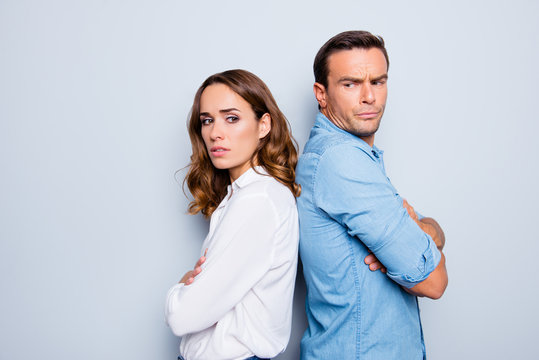 Adult mature sad, upset couple in shirts, casual outfit having family conflict, standing back to back with crossed arms ignoring each other over grey background