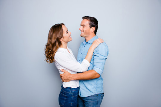 He vs she happy together. Close up portrait of cute, mature couple in shirts, casual outfit hugging, looking to each other, standing over grey background