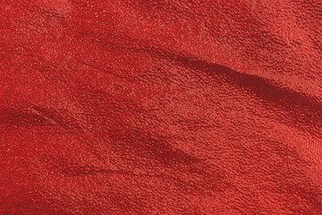 A piece of red metallic cloth that is wrinkled.