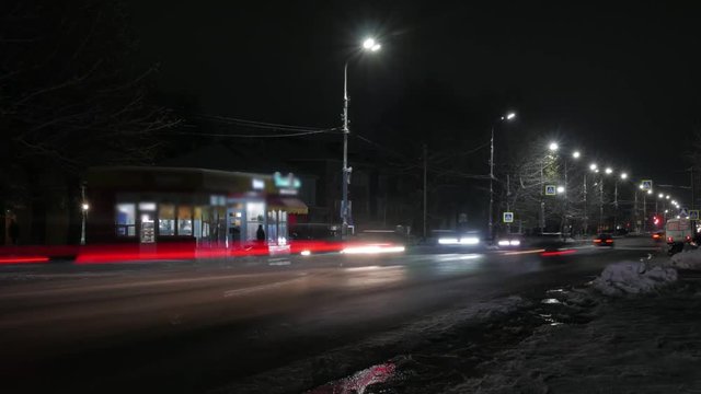 Time lapse of the winter night road in the city. Dirty roadside snow.