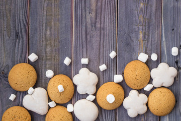 Fototapeta na wymiar border of white and brown gingerbread with marshmallows on wooden background