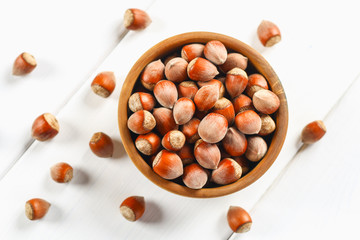 Hazelnut nuts in a wooden bowl on a white wooden table. Superfood.