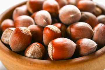 Hazelnut nuts in a wooden bowl on a white wooden table. Superfood.