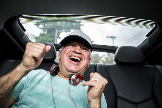 Happy senior man listening music in the car