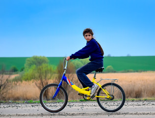 Naklejka premium Girl riding a bike and looking at the camera on a nature background