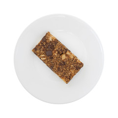 Top view of an almond butter chocolate nut bar on a plate isolated on a white background.
