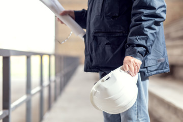 Close up of senior construction worker holding hardhat.