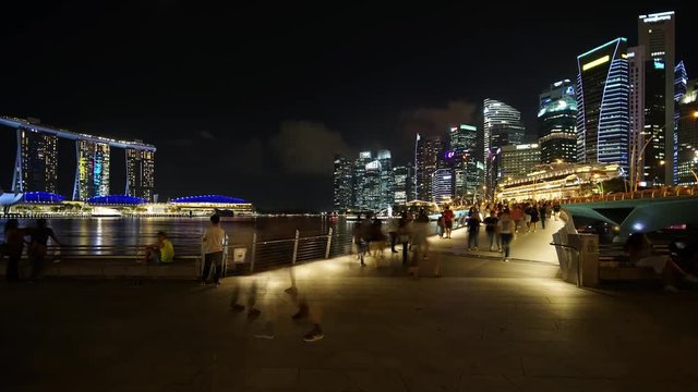 Singapore - November 27, 2017: Zoom in timelapse of Singapore cityscape and pedestrian at night from Esplanade Bridge. Shot in 4k resolution