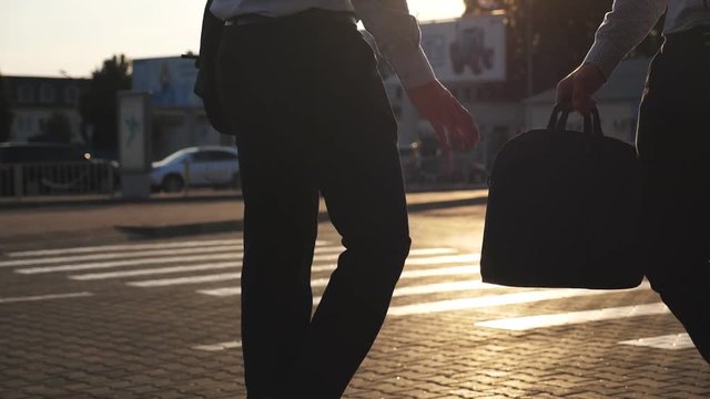 Business man unnoticeably passing a black briefcase to his partner. Unrecognizable colleagues in the city background. Two young businessmen meeting outdoor. Close up Slow motion