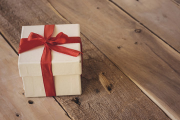 small white gift box with red ribbon on wood table