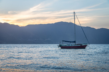 Sailboat at sunset with Sao Sebastiao on background - Ilhabela, Sao Paulo, Brazil