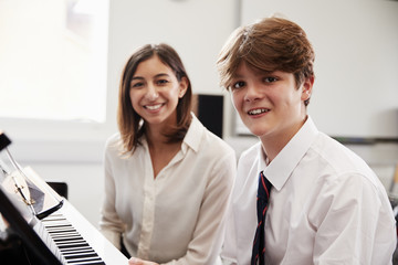 Fototapeta premium Portrait Of Pupil With Teacher Playing Piano In Music Lesson