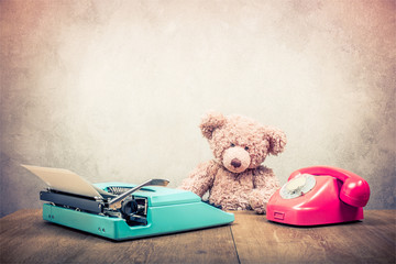 Teddy Bear toy sitting at the old wooden desk with mint green retro typewriter and telephone circa...