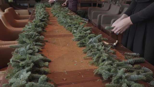Florist at work: woman hands making christmas decorations garland of fir Nobilis. Happy new year dinner feast