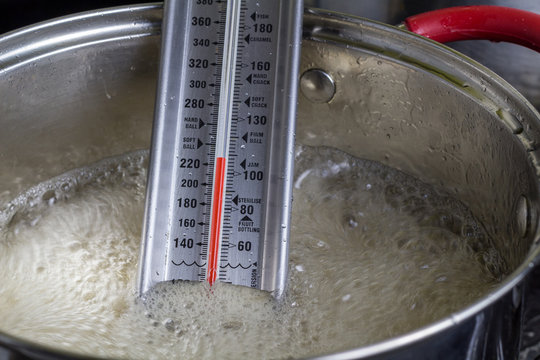 Candy Thermometer In Modern Metal Pot With Red Handles With Boiling Apple Jelly