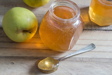 Apple jelly jam on wooden table with apples - selective focus on jar