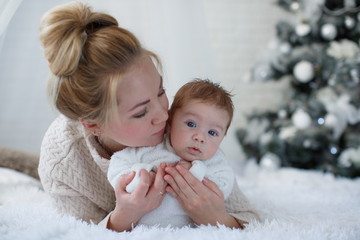 Happy young mother and her son playing at home during Christmas holidays.Christmas family portrait of a young beautiful woman with a newborn son.