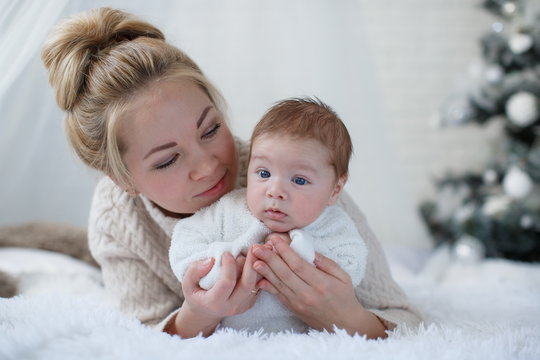Happy young mother and her son playing at home during Christmas holidays.Christmas family portrait of a young beautiful woman with a newborn son.