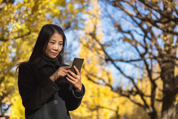 Fototapeta na wymiar Woman using mobile phone in Autumn
