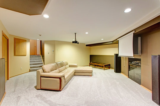 Beige basement movie room with a leather sectional