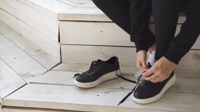 Woman putting on and lacing trainers. Athlete preparing for workout outdoor