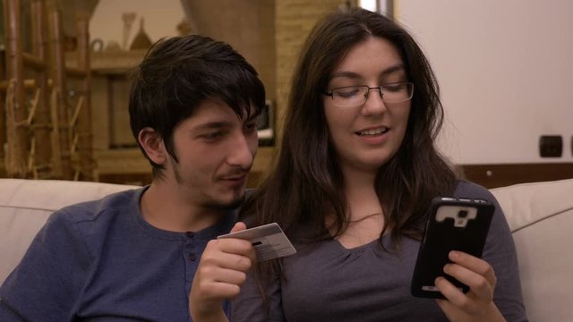 Attractive Brunette Woman Holding Smart Phone And Introducing Credit Card Data To Shop Online