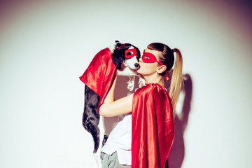 side view of woman kissing puppy in superhero costume