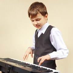 Little beginner pianist in a suit playing the digital piano