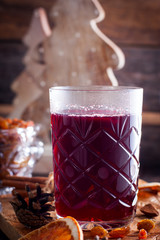 Scandinavian hot alcoholic drink with cinnamon in a glass cup on a wooden board, selective focus